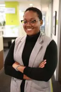 Teshini Harrison stands in a hallway, smiling