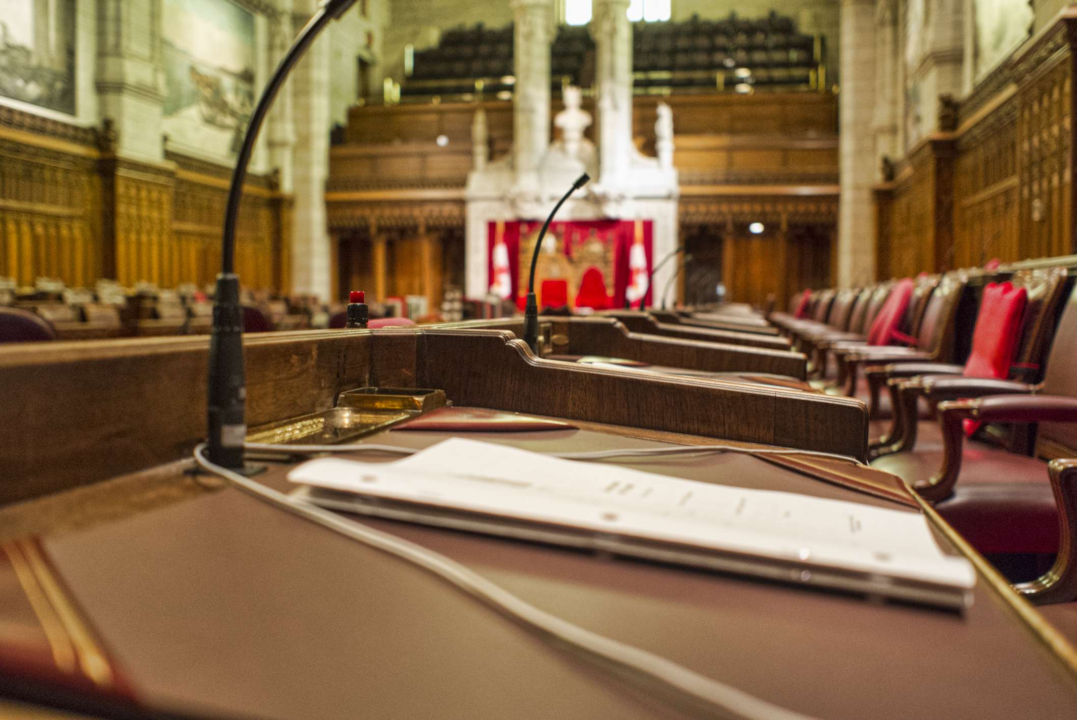 Close up of a Senator's desk with paperwork. Image taken in the chambers of the Senate of Canada, in the Parliament Buildings in Ottawa, Canada. The Speaker's chair can be seen in the background. A narrow depth off field has been applied to this image.