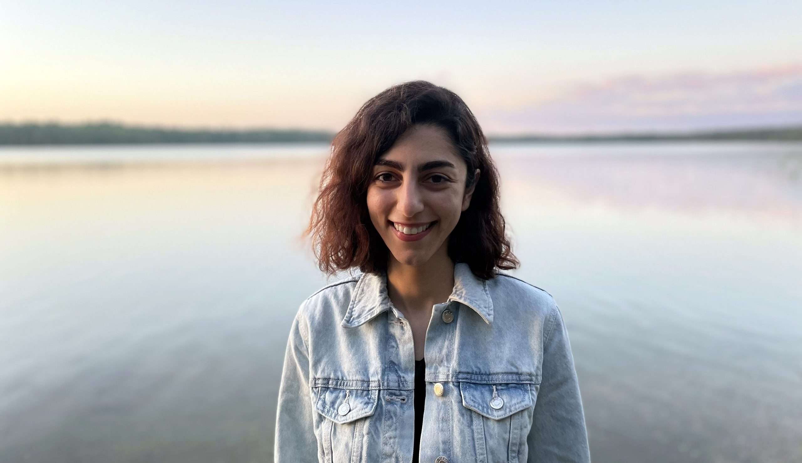 Photo of Maryam standing in front of a lake