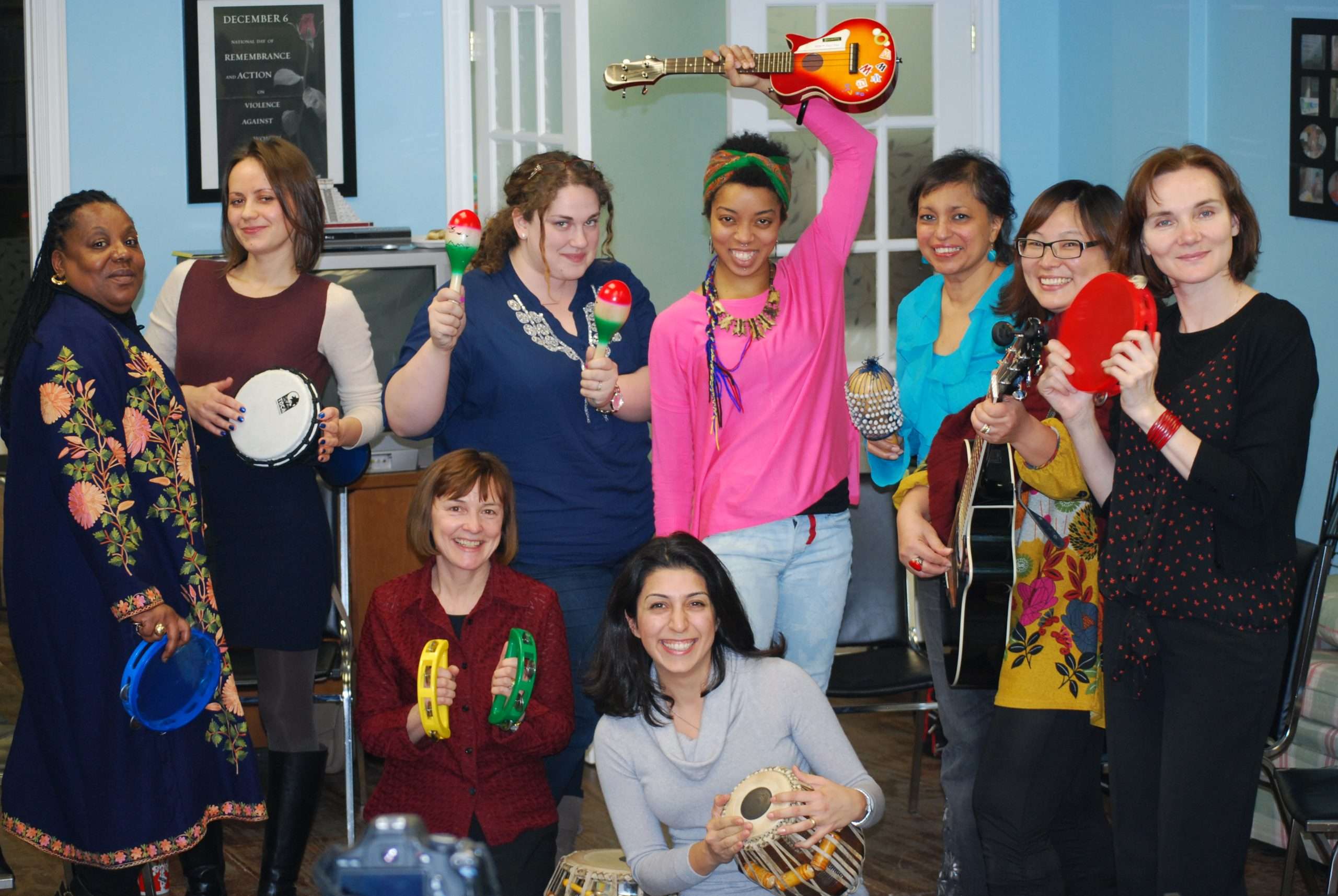 Group of women smiling and holding different musical instruments